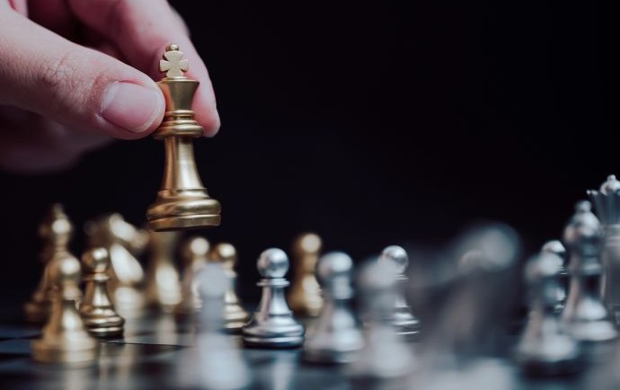 hand picking up a chess piece from a chess board